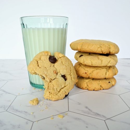 Pile de biscuit à arachide, un biscuit mordu accoté à un verre de lait.