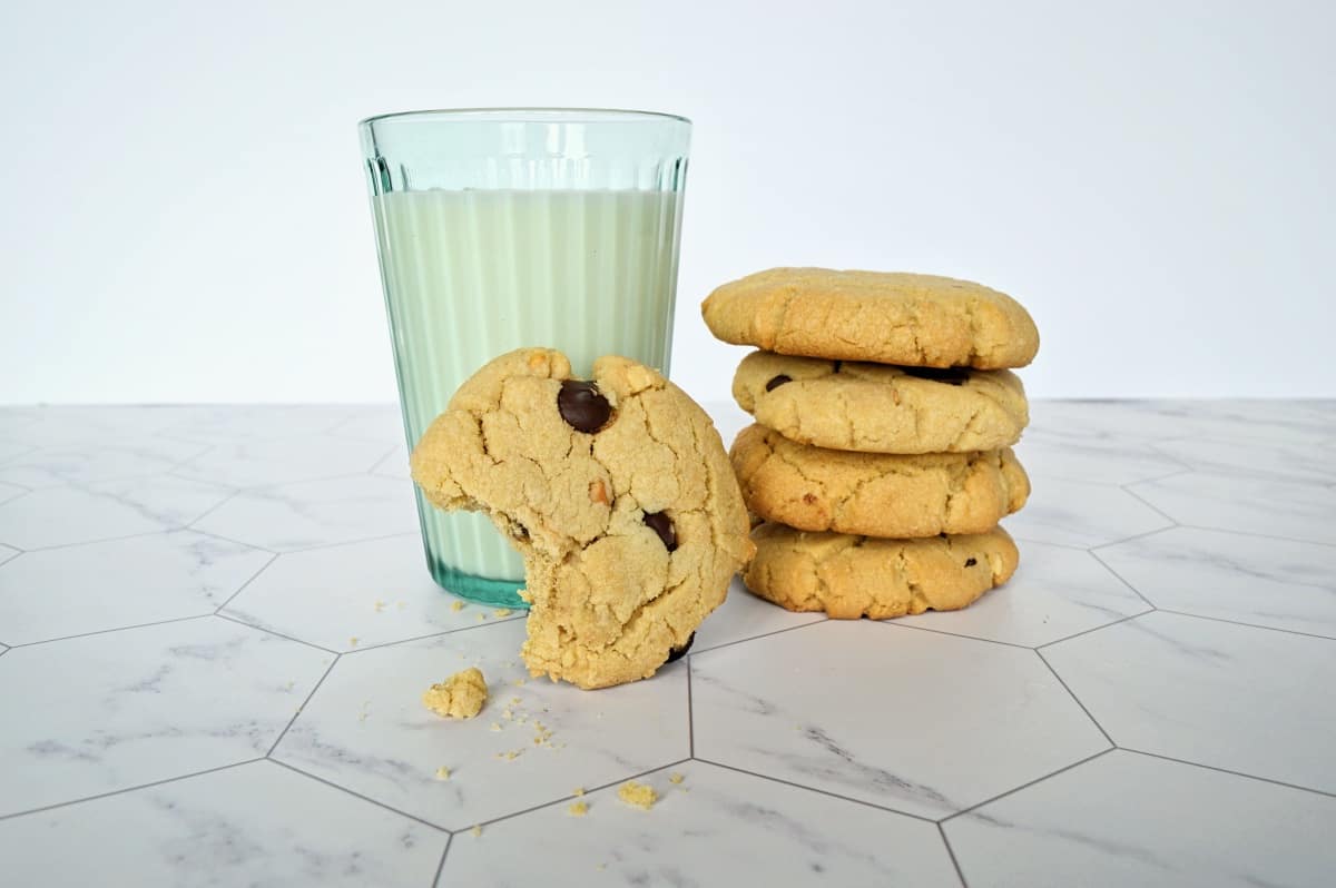 Pile de biscuits au beurre d'arachide, un biscuit mordu accoté à un verre de lait.