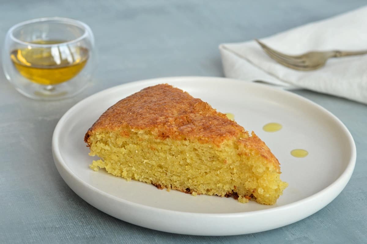 Tanche de gâteau à l'huile d'olive, récipient avec huile d'olive en arrière, fourchette et serviette à main.