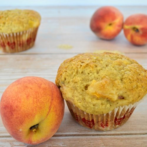 3 pêches et 2 muffins sur un fond de bois.