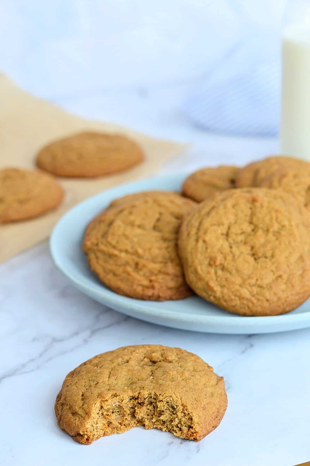 Biscuits à la mélasse et gingembre dans une assiette, un biscuit avec une morsure, un verre de lait derrière.